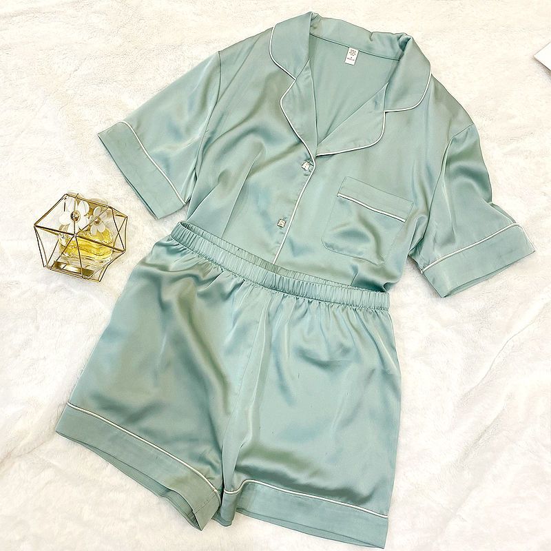 Mint green satin pajama set on a white surface with a small decorative item.