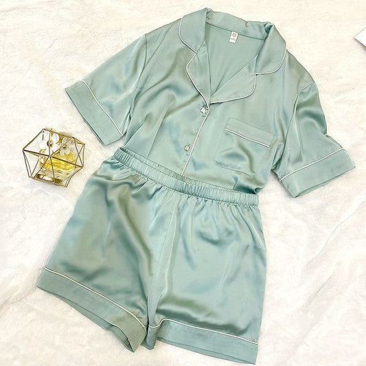 Mint green satin pajama set on a white surface with a small decorative item.